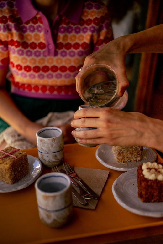 Hands pouring water into drinking glasses